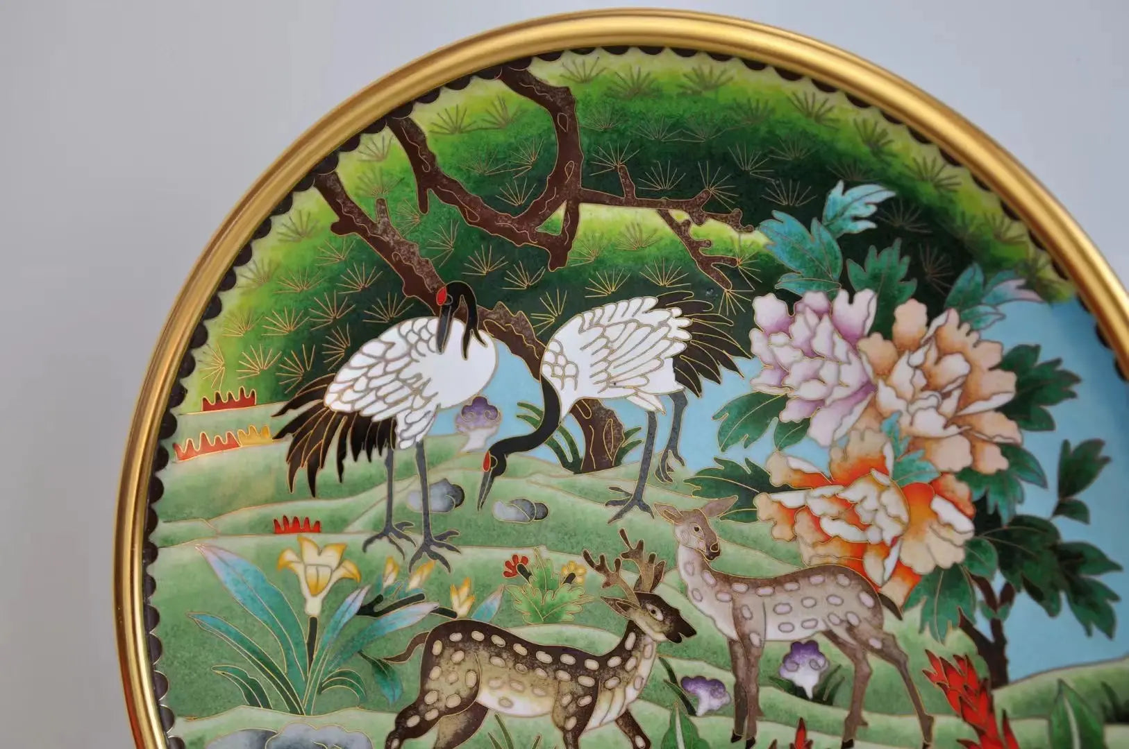 Macro close-up of the Cloisonné plate showing intricate gold wire filigree and vibrant enamel details of the white cranes and floral patterns.