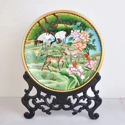 Full front view of the handcrafted Cloisonné decorative plate with crane and deer landscape, displayed on a traditional black carved wood stand.
