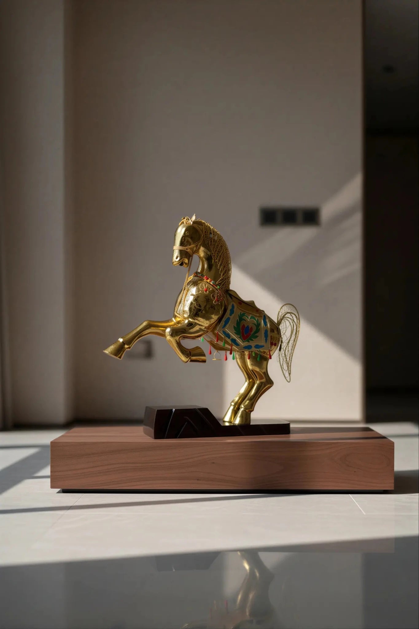 A handcrafted gold cloisonné enamel horse statue with intricate filigree details, displayed on a wooden table.