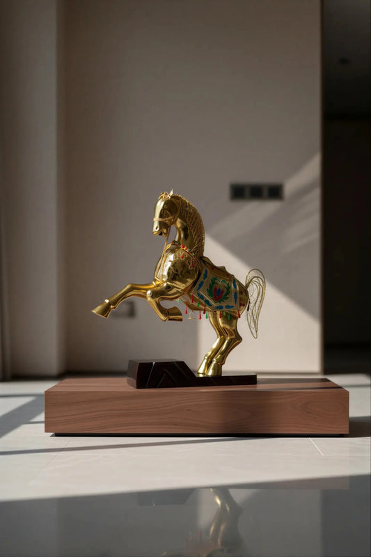 A handcrafted gold cloisonné enamel horse statue with intricate filigree details, displayed on a wooden table.