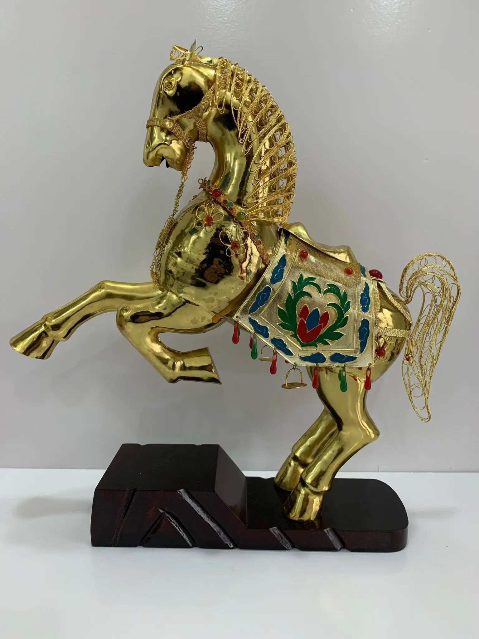 Handcrafted Cloisonné golden horse statue in a triumphant rearing pose, featuring 24K gold-plated filigree and vibrant enamel saddle, displayed on a dark walnut wood base.